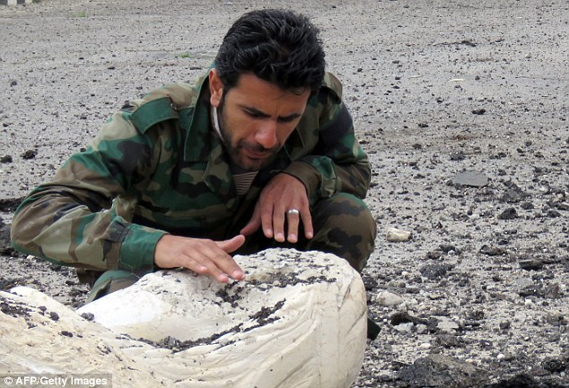 Barbarity: A Syrian soldier inspects a damaged statue in Palmyra, which has been systematically taken apart by ISIS thugs since they occupied the city since May 2015